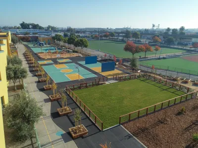 Aerial view of schoolyard in Oakland, California with newly planted trees, sports courts, and playground equipment.