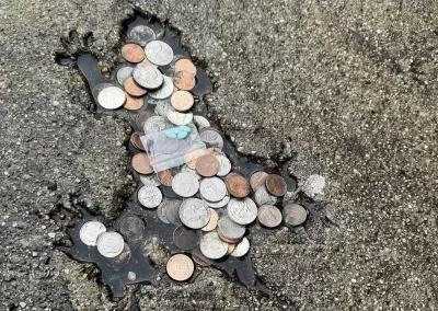 Rat shaped indentation on pavement, filled with coins