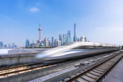 A high-speed rail is blurred as it passes a modern skyline in China.