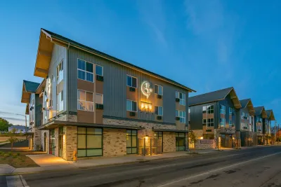Three-story apartment complex with pitched roofs at dusk.