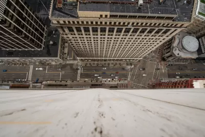 A busy urban street is seen from the vantage point offered by looking straight down from the top of a high-rise.