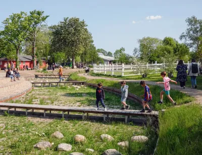 Children walking on a wooden walkway over green creek bed in Copenhagen, Denmark.