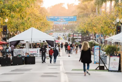 People walking down Main Street Ventura, California with white canopies on either side.