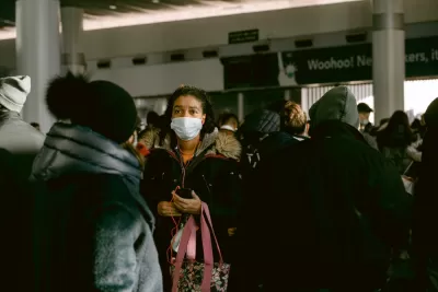 A woman wears a mask during the Covid-19 pandemic in a large crowd at a transit station in New York City.