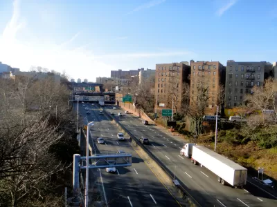A view of the Cross Bronx Expressway, an elevated highway that allows cars to drive past apartment buildings.