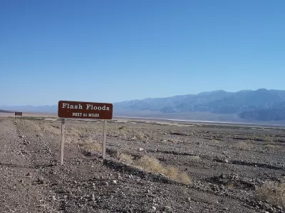 Brown and white "flash floods: next 55 miles" road sign in Death Valley, California
