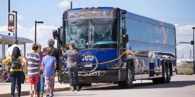 Passengers boarding a blue Flatiron Flyer BRT bus in Denver, Colorado.