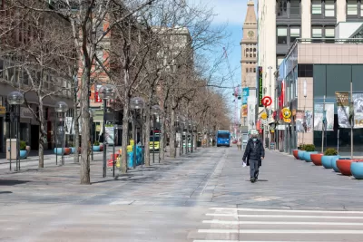 One man, wearing a mask, walks down an otherwise empty 16th St in Denver.
