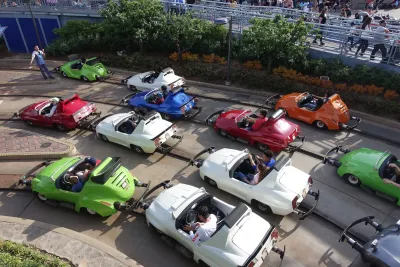 Aerial view of several multicolored Autopia cars on tracks with riders in Disneyland.