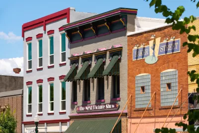 A row of multistory, brick buildings in a small U.S. city, with retail uses on the ground floor and apartments above.