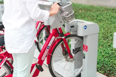 Close-up of person checking out bike at Houston BCycle station with red bikes