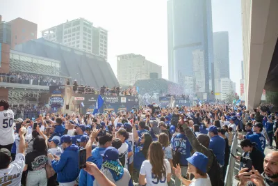 Crowd of LA Dodgers fans in downtown Los Angeles waving pennants, celebrating a win.