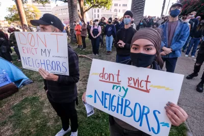 Protestors gather with signs that read “Don’t Evict My Neighbors.” 