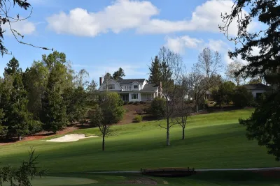 Large house on golf course in Los Altos Hills, California with blue sky with fluffy clouds.