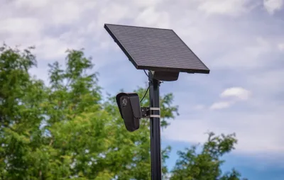 Close-up on black Flock surveillance license plate reader camera with solar panel.