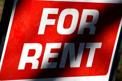 Close-up of FOR RENT sign with white text on bright red background.