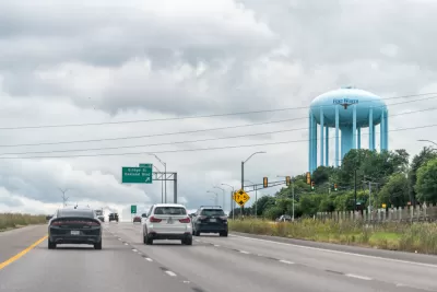 A view of a large water tower, with the words and logo of Fort Worth, looming over a wide freeway.