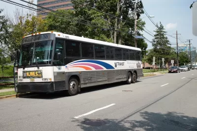 White NJ Transit parked at station with blue stripes.