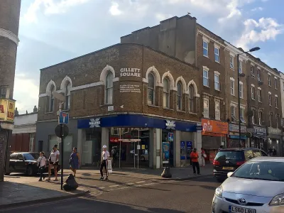 Intersection with sign for Gillett Square in East London, UK with brick buildings with ground floor storefronts.