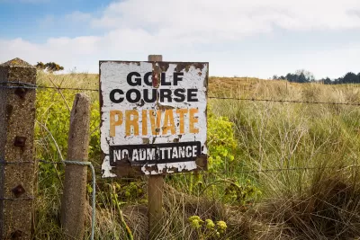 A derelict sign on a barbed wire fence reads “Golf Course, Private, No Admittance.”