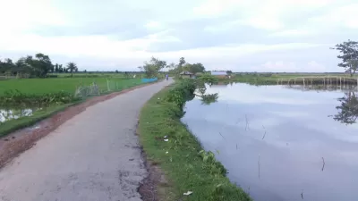 Paved rural road in developing country with water on either side.