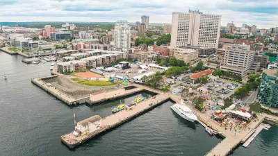 Aerial view of Halifax Waterfront with people milling around on docks among yellow umbrellas and business patios.