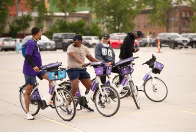 Four people standing on Heartland bike share bikes and talking to each other.