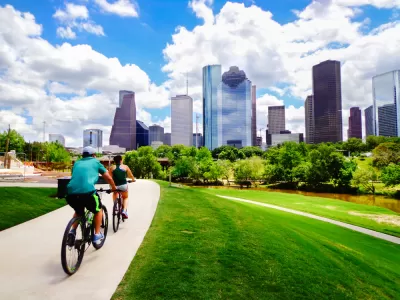 Two people on a bike trail with downtown Houston in the background
