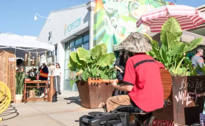 Musician playing guitar in front of outdoor seating and sidewalk vendors in Houston, Texas