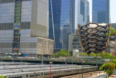 Numerous trains are lined up at the Hudson Yards train depot with the fancy architecture of Hudson Yards in the background.