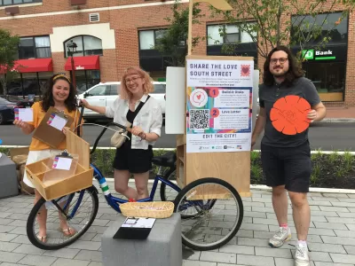 A group of people gather around an information booth to share ideas about the future of South Street in Philadelphia. 