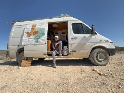 Charles Gandy sitting in the open side door of a white van with map of Texas inside door.
