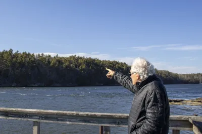 A man points at trees over water
