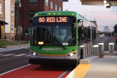 Green rapid transit bus pulled into station in dedicated lane.