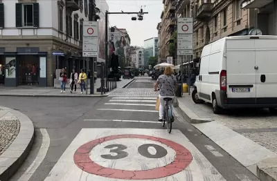 A bike rider navigates a bike lane in a traffic limited zone in Italy, where only one delivery van is visible on the street.