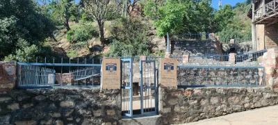 Historic stone structure surrounding natural spring in India with plaques.