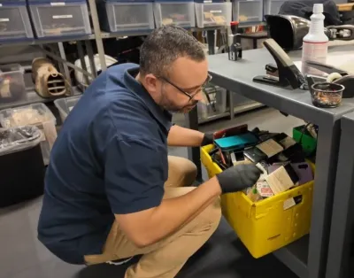 Man in blue shirt looking into yellow lost and found bin at Los Angeles Metro office.