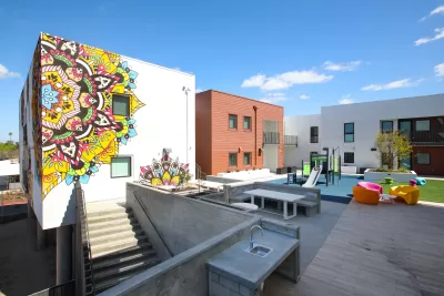 The interior of a multi-story apartment building includes a children's' playground and a colorful mural.