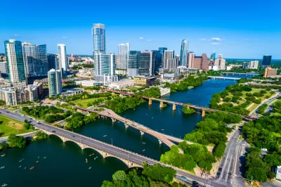 Downtown Austin with Lady Bird Lake in the foreground. Multiple bridges are crossing the lake and small personal water-crafts dot the water.