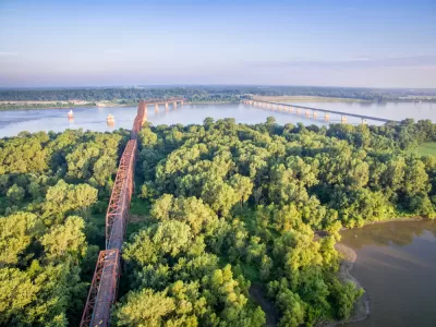 Two bridges cross the Mississippi Rivera midst thick vegetation and few other signs of human intervention.