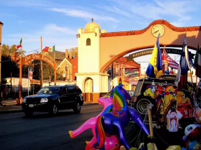 Spanish-style arch over street reading 'Bienvenidos a Little Village" in Chicago, Illinois at golden hour.
