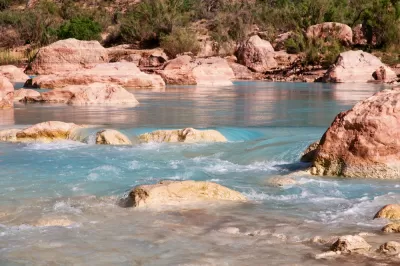 A river runs blue through the red rocks of the desert.