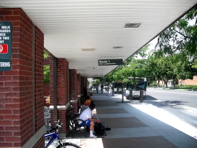 People waiting under covered brick bus shelter in Logan, Utah.