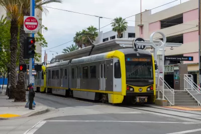 A light rail train waits at the Downtown Long Beach station with a sign that reads “Long Beach” to declare its route to riders.