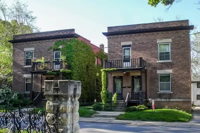 Side-by-side brick duplexes pictured on a sunny day.