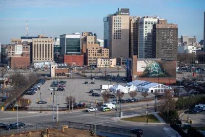 Parking lot in downtown Detroit, future home of university of michigan center for innovation, with mural of Statue of Liberty's head on building behind lot.