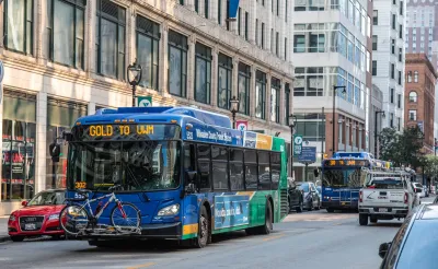 Blue Milwaukee transit bus on street next to large brick buildings.