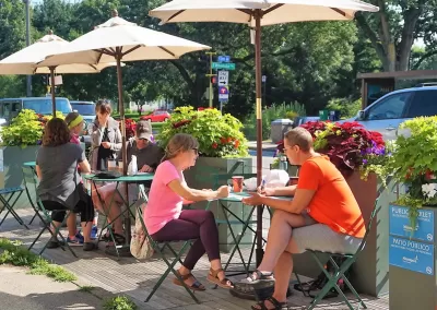 People sitting at small tables in a public parklet in Minneapolis, Minnesota.