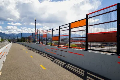 A bike lane protected by concrete barrier on bridge in Salt Lake City with colorful public art running alongside.