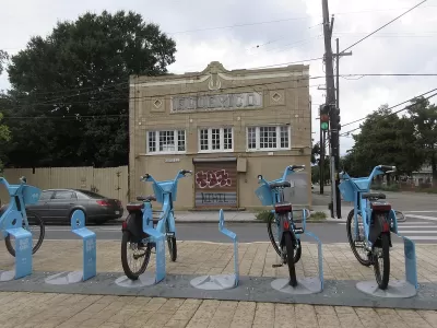 Row of blue Blue Bikes bike share bikes at docked station on sidewalk in New Orleans, Louisiana.